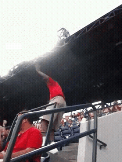 Man In Red Shirt Standing On Railing At Baseball Stadium GIF