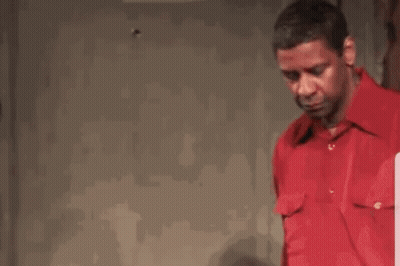 Man in Red Shirt Talking to Another Man in Dark Room