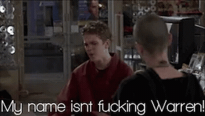 Man In Red Shirt Talking To Another Man In Front Of TV Saying My Name Isn't Fucking Warren GIF