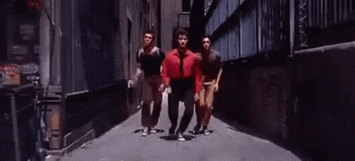 Man In Red Shirt Walking Down Alley With Two Men GIF