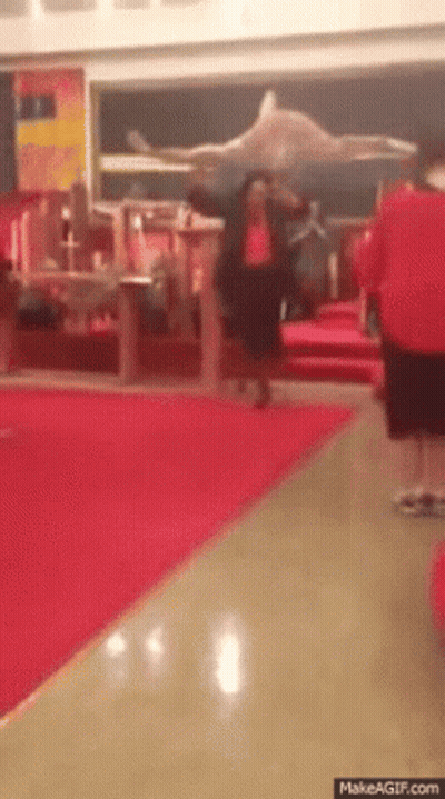 Man In Red Shirt Walking Down Hallway With Red Carpet GIF