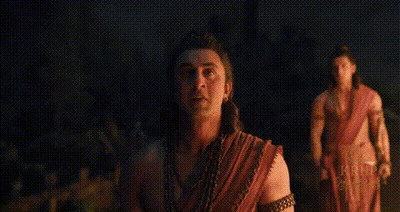 Man In Red Shirt Walking Through Green Forest GIF