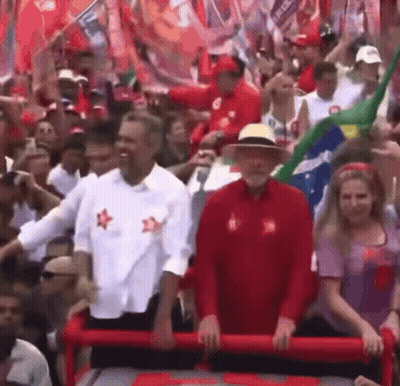 Man In Red Shirt With Star Standing Before Crowd GIF