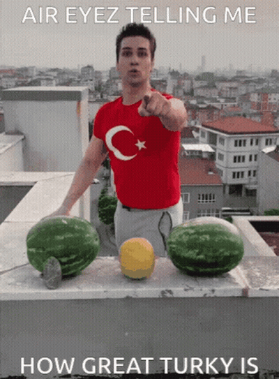 Man In Red Shirt With Turkish Flag Points At Two Watermelons GIF