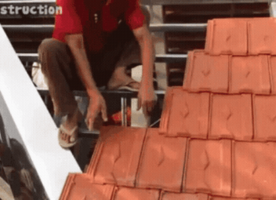 Man In Red Shirt Working On Tiled Roof GIF