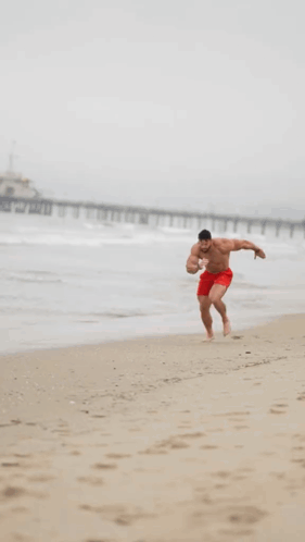 Man In Red Shorts Running On Beach GIF