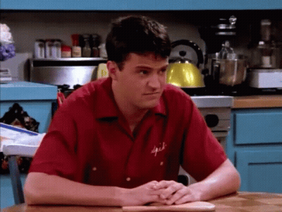 Man In Red Spice Shirt Sits At Table GIF
