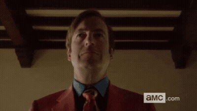Man In Red Suit Holding Black Briefcase With AMC.com Sign GIF