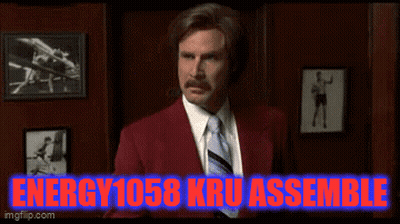Man In Red Suit Standing In Front Of Energy 1058 Kru Assemble Sign GIF