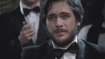 Man In Red Suit Talking To Man In Black Tuxedo GIF