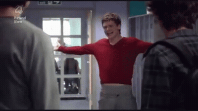 Man In Red Sweater Arms Outstretched In Front Of Exit Sign GIF