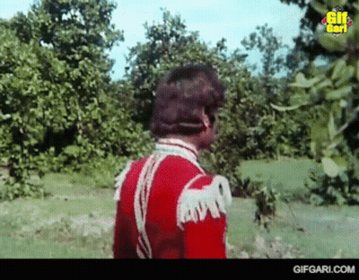 Man In Red Uniform Standing In Grassy Field GIF