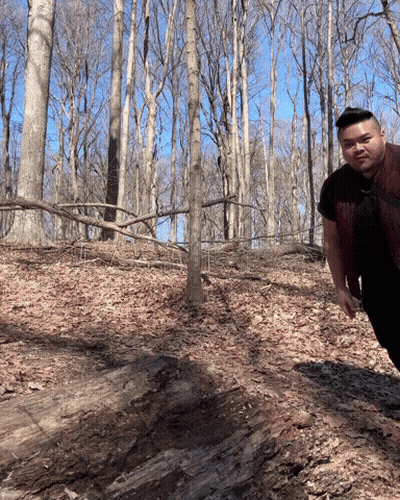 Man In Red Vest Standing In Woods GIF