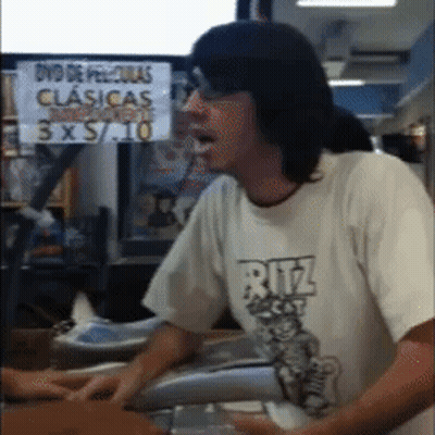 Man In Ritz Shirt Standing In Front Of DVD De Peliculas Clasicas 3X5 10 Sign GIF