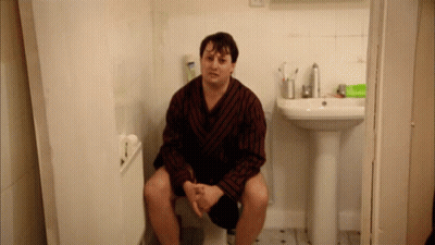 Man In Robe On Toilet Beside Bathroom Sink GIF