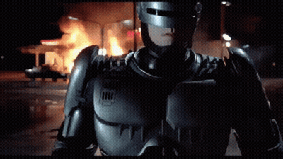 Man In Robot Costume In Front Of Fire GIF