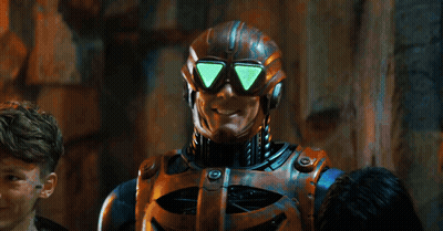 Man In Robot Costume Standing In Front Of Here's Sign GIF