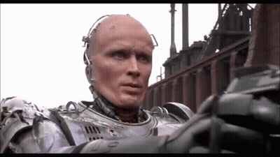 Man In Robot Suit In Front Of Factory GIF