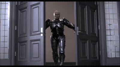 Man In Robot Suit Standing In Doorway With Arms Outstretched GIF