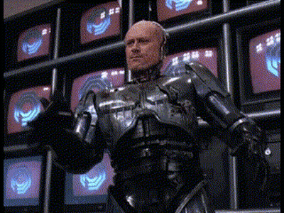 Man In Robotic Suit In Front Of TV Wall GIF