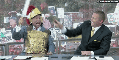 Man In Roman Helmet Holding Sword In Front Of Suited Man GIF