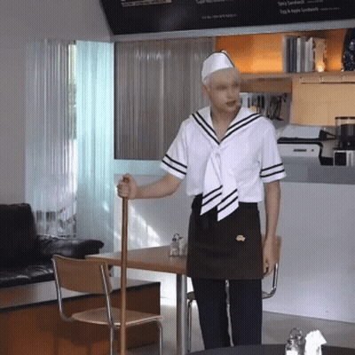 Man In Sailor Outfit Holding Cane In Front Of Spicy Sandwich Sign GIF