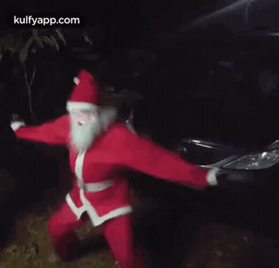 Man In Santa Costume Dancing In Front Of Car GIF