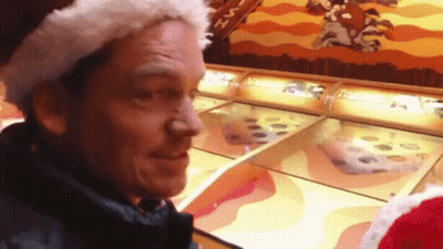Man In Santa Hat Playing Game At Amusement Park GIF