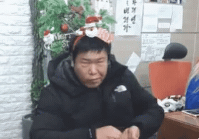 Man In Santa Headband By Christmas Tree GIF