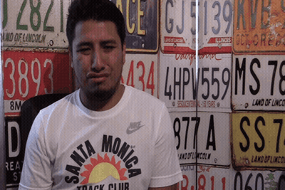 Man In Santa Monica Track Club Shirt In Front Of License Plates GIF