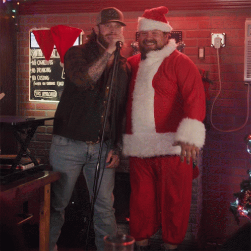 Man In Santa Suit Next To Man Singing GIF