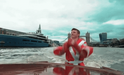 Man In Santa Suit Riding Boat GIF