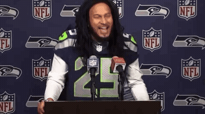 Man In Seahawks Jersey At Podium In Front Of NFL Logo GIF