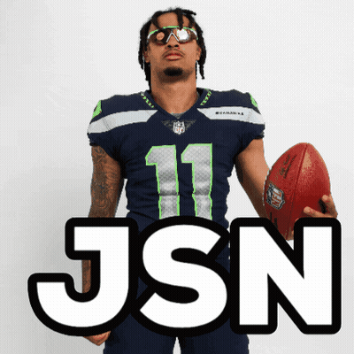 Man In Seahawks Jersey Holding Football In Front Of JSON Sign GIF