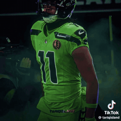 Man In Seahawks Uniform Smiling In Front Of Scoreboard Saying 1:49 GIF