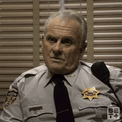 Man In Sheriff's Uniform Sitting By Shutters GIF