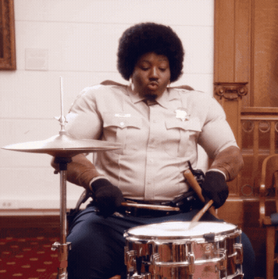 Man In Sheriff Uniform Playing Drum Set GIF