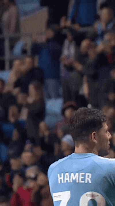Man In Shirt With Hammer On Back In Front Of Crowd GIF