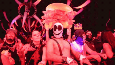 Man In Skull Mask Holding Inflatable Hamburger On Head GIF