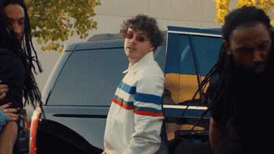 Man In Striped Jacket In Front Of SUV GIF