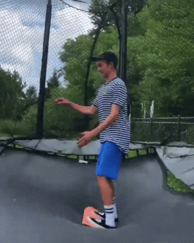 Man In Striped Shirt, Blue Shorts, And Nike Shoes On Trampoline GIF