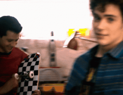 Man In Striped Shirt Holding Checkered Skateboard GIF