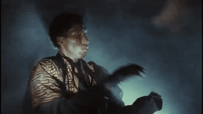 Man In Striped Shirt Holding Gun In Dark Room GIF