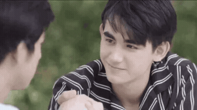Man In Striped Shirt Holding Hand And Smiling GIF