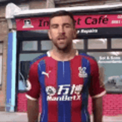 Man In Striped Shirt In Front Of Building GIF