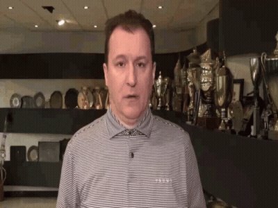 Man In Striped Shirt In Front Of Trophy Wall GIF