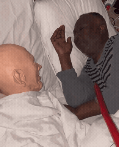 Man In Striped Shirt Laying In Hospital Bed Next To Another Man GIF