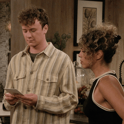 Man In Striped Shirt Looking At Paper Next To Woman GIF