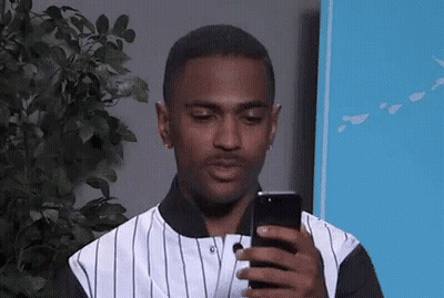 Man in Striped Shirt Looking at Phone