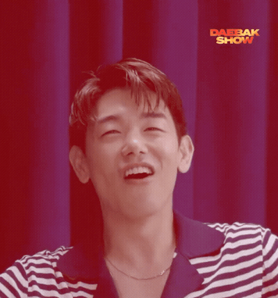 Man In Striped Shirt Smiling In Front Of Red Curtain Saying Daebak Show GIF
